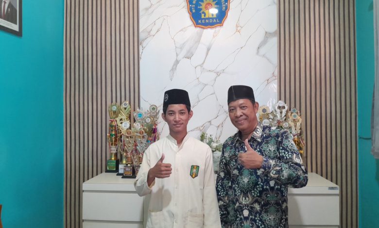 Bagus Satrio Aji, siswa MTs Muhammadiyah 1 Weleri hafal 30 Juz, berfoto bersama Kepala Madrasah Sugiarto di depan deretan piala prestasi.