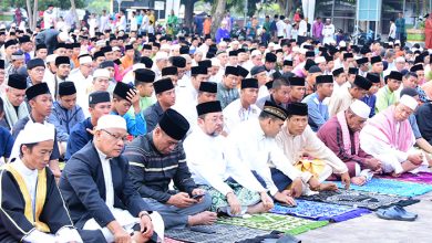 Jamaah Muslim mengikuti salat Idul Fitri berjamaah di area terbuka dengan mengenakan pakaian muslim dan peci.