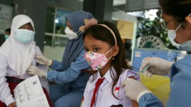 Tenaga kesehatan memberikan vaksin kepada seorang anak sekolah dasar dalam kegiatan imunisasi sebagai upaya melindungi diri dan membentuk kekebalan komunitas.