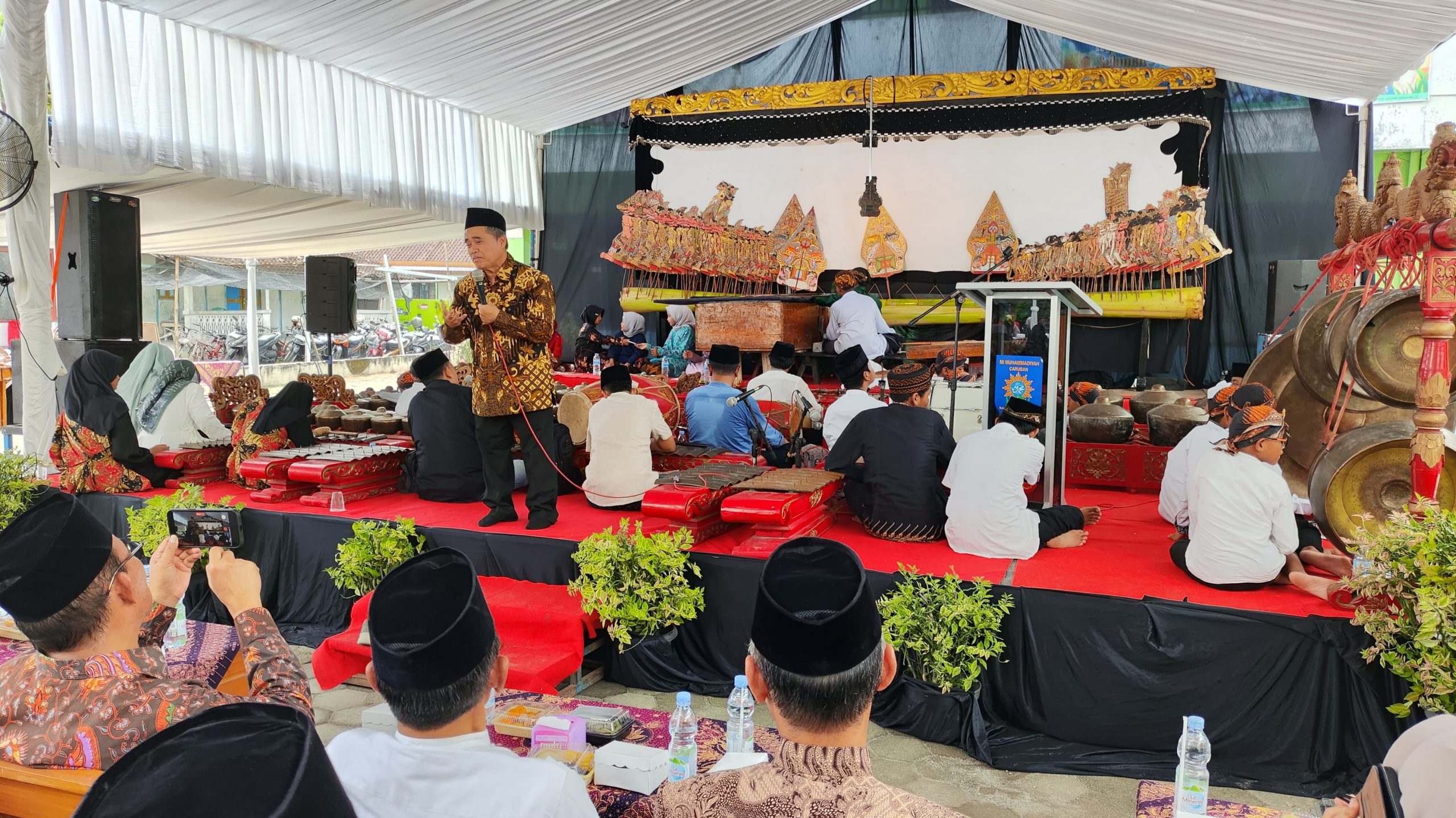 K.H. Tafsir menyampaikan tausiah pada acara Halalbihalal di Masjid Ath Thalhah, Mojorejo, Madiun, dengan latar pertunjukan wayang kulit dan gamelan.