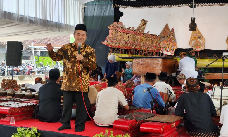 Seorang penceramah menyampaikan tausiah pada acara Halalbihalal di Masjid Ath Thalhah Mojorejo, Madiun, dengan latar pertunjukan wayang kulit dan gamelan.