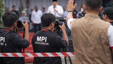 Awak media MPI Pekalongan mengambil gambar dari area terbatas saat kunjungan Mendikdasmen di Kabupaten Pekalongan, dengan pembatas protokol di depan area peliputan.