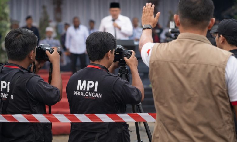 Awak media MPI Pekalongan mengambil gambar dari area terbatas saat kunjungan Mendikdasmen di Kabupaten Pekalongan, dengan pembatas protokol di depan area peliputan.