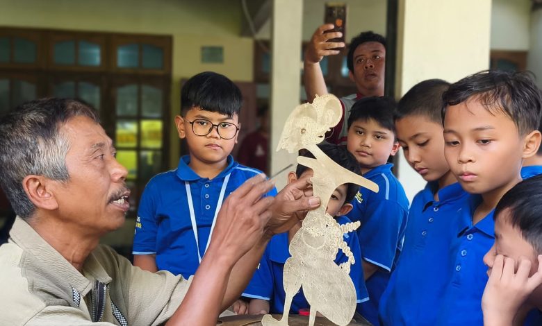 Perajin wayang kulit menunjukkan proses tatah sungging kepada murid SD Muhammadiyah PK Kottabarat Solo saat field trip budaya di Bantul.