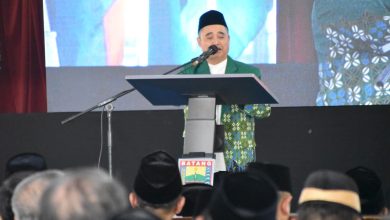 Dr. KH. Tafsir, M.Ag. memberikan sambutan di podium berlogo "BATANG" saat acara Halalbihalal PWM Jawa Tengah, mengenakan jas batik Muhammadiyah berwarna hijau dan peci hitam, dengan latar belakang layar besar yang menampilkan wajahnya.
