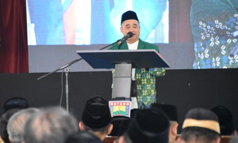 Dr. KH. Tafsir, M.Ag. memberikan sambutan di podium berlogo "BATANG" saat acara Halalbihalal PWM Jawa Tengah, mengenakan jas batik Muhammadiyah berwarna hijau dan peci hitam, dengan latar belakang layar besar yang menampilkan wajahnya.