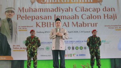 Dr. KH. Tafsir, M.Ag., Ketua PWM Jawa Tengah, sedang menyampaikan tausiah dengan mic di panggung, didampingi dua anggota KOKAM berseragam militer dan baret merah, di acara Silaturahmi Muhammadiyah Cilacap dan Pelepasan Jemaah Haji KBIHU Al Mabrur.