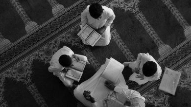 Foto hitam putih sekelompok orang sedang duduk melingkar di dalam masjid sambil membaca dan mendiskusikan Al-Qur’an sebagai ilustrasi kajian tafsir Islam.