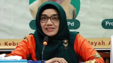 Dr. Hj. Umul Baroroh, M.Ag. saat berbicara dalam sebuah forum, mengenakan busana oranye dan jilbab hijau.