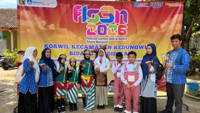 Siswa dan guru pembimbing SD Muhammadiyah Tangkil Tengah berfoto bersama di depan banner FLS3N 2026 Kecamatan Kedungwuni setelah memenangkan empat piala lomba seni.
