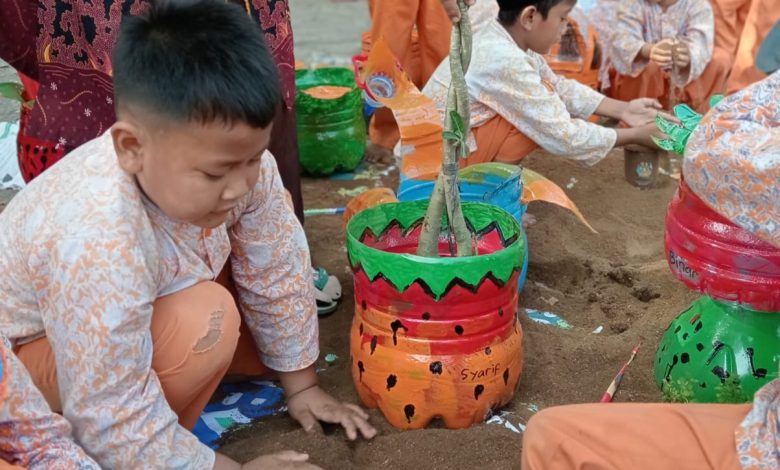 Siswa TK Aisyiyah 09 Jepara sedang mempraktikkan edukasi lingkungan anak usia dini dengan menanam bunga menggunakan pot dari galon bekas yang telah dilukis kreatif.