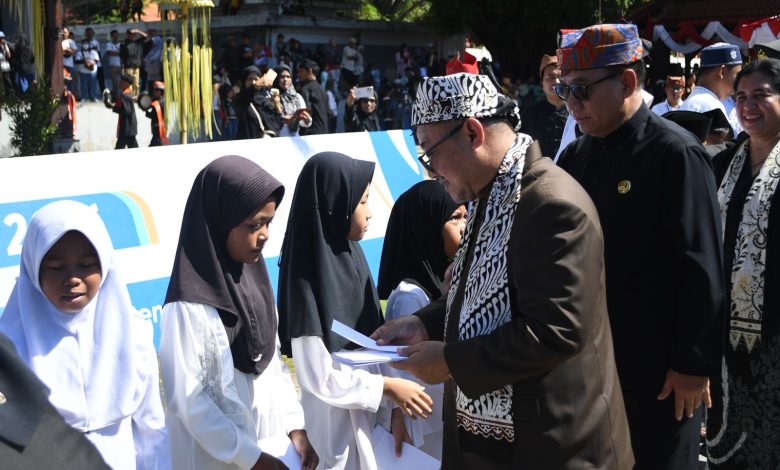 Mendikdasmen Abdul Mu’ti memberikan santunan kepada siswi sekolah dasar saat peringatan Hardiknas 2026 di Banyuwangi.