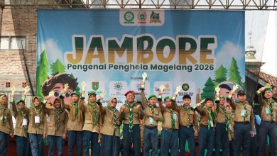 Para pemenang lomba Jambore Hizbul Wathan Magelang 2026 berpose di atas panggung sambil mengangkat trofi penghargaan di depan latar belakang spanduk acara.