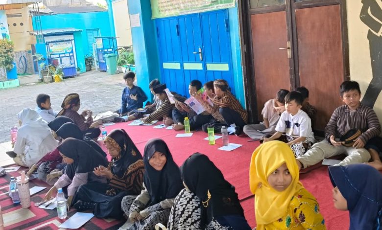 Siswa-siswi MIM Kauman Wiradesa duduk bersama di atas karpet merah dalam kegiatan literasi Hari Pendidikan Nasional 2026.