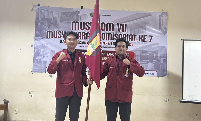 Dua kader PK IMM Al-Fatih FTIK UMPP berpose mengenakan jas merah IMM sambil memegang bendera organisasi dalam acara Musykom VII di Pekalongan.