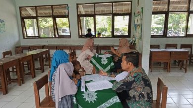 Suasana asesmen calon murid baru di MI Muhammadiyah Purwodadi. Seorang guru pria (kanan) mewawancarai orang tua di meja dengan taplak hijau berlogo Muhammadiyah, sementara dua calon siswa menunggu antrean di sebelah kiri. Di latar belakang, dua guru wanita juga melakukan sesi wawancara.