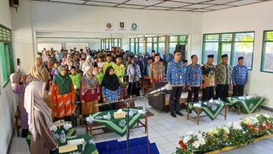 Suasana pembukaan Festival Sains dan Al-Qur’an SMP Muhammadiyah Jono di aula Komplek Pondok Pesantren Darul Arqom Muhammadiyah Bayan. Gambar menunjukkan barisan depan tamu undangan, termasuk Pimpinan Muhammadiyah dan perwakilan Dinas Pendidikan, berdiri di depan ratusan siswa SD/MI yang menjadi peserta. Aula terang, dengan dekorasi panggung bunga di latar depan dan beberapa spanduk kecil organisasi Muhammadiyah di dinding.