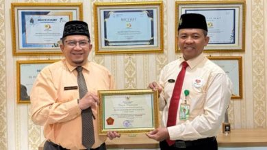 Dua pria berpeci menunjukkan piagam penghargaan Platinum P2HIV/AIDS dari Menteri Ketenagakerjaan RI untuk RS PKU Muhammadiyah Surakarta.