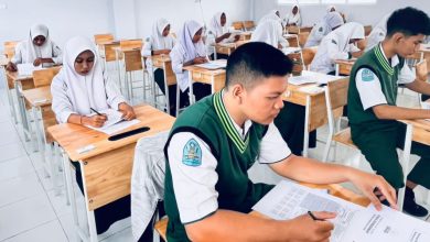 Foto suasana outdoor acara peresmian Jurusan Manajemen Perkantoran di SMK Muhammadiyah Aceh. Di panggung, tampak spanduk peresmian berwarna merah-putih-kuning. Banyak tamu undangan duduk di bawah tenda dengan dekorasi senada, dihiasi dedaunan pohon mangga di latar depan. Seorang kameramen sedang mendokumentasikan acara.