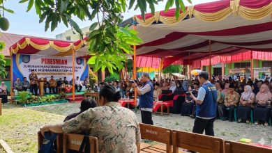 Suasana peresmian Jurusan Manajemen Perkantoran SMK Muhammadiyah Aceh di area terbuka dengan tenda merah kuning, spanduk besar di panggung, dan tamu undangan yang hadir.