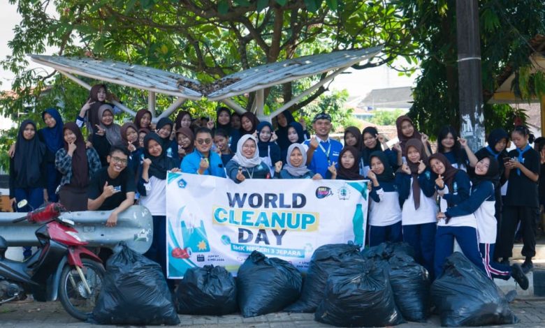 Siswa dan guru SMKN 3 Jepara berfoto bersama membawa spanduk World Cleanup Day 2026 dengan tumpukan kantong sampah hitam di depan mereka sebagai hasil aksi kebersihan lingkungan.