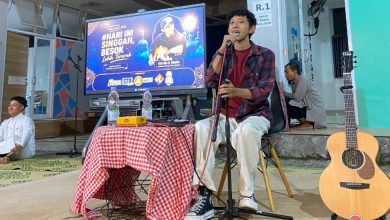 Dio A Diadon memegang mikrofon saat mengisi Kajian Pemuda Colomadu dengan latar belakang layar digital acara.