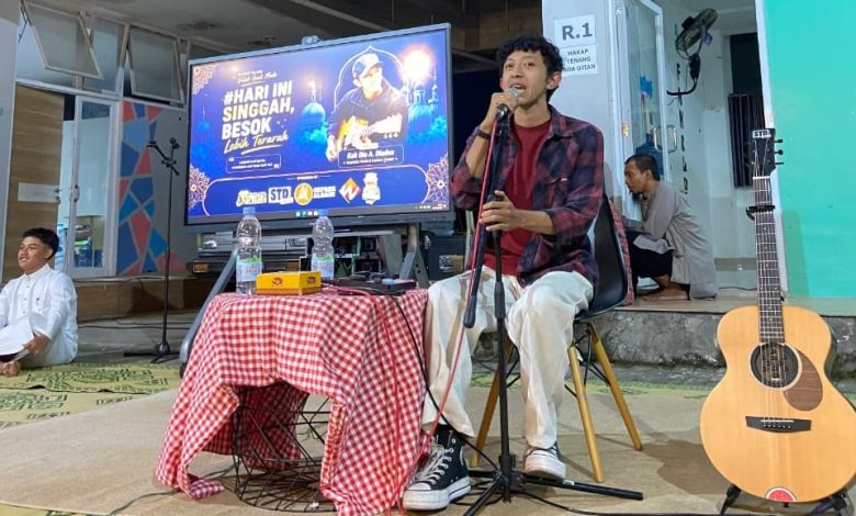 Dio A Diadon memegang mikrofon saat mengisi Kajian Pemuda Colomadu dengan latar belakang layar digital acara.