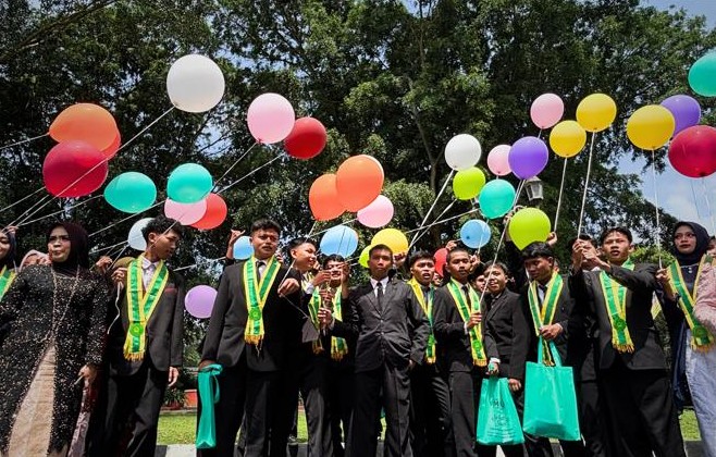 Wisudawan SMK Muhammadiyah 1 Temanggung berfoto dengan balon di area terbuka.