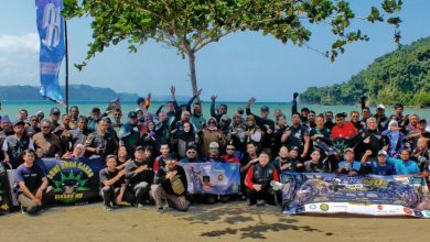 Sekelompok besar pengendara sepeda motor (bikers) berfoto bersama di pantai tropis dengan bendera BikersMu dan spanduk Kopdargab VI.