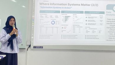 Seorang mahasiswi SIF UMS mengenakan hijab berbicara dengan mikrofon di depan layar proyektor yang menampilkan materi tentang analisis sistem informasi dalam kegiatan sarasehan prodi.