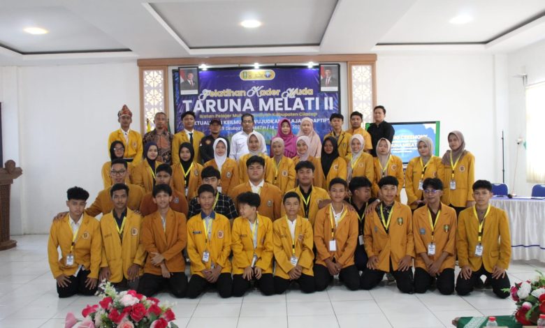Foto bersama peserta dan panitia Pelatihan Kader Muda Taruna Melati II IPM Cilacap mengenakan jas almamater kuning di aula kegiatan.