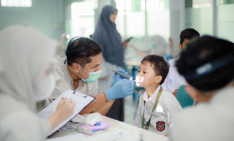 Mahasiswa profesi dokter gigi FKG UMS sedang melakukan pemeriksaan atau screening kesehatan gigi pada seorang siswa SDIT Nur Hidayah Surakarta menggunakan senter medis.
