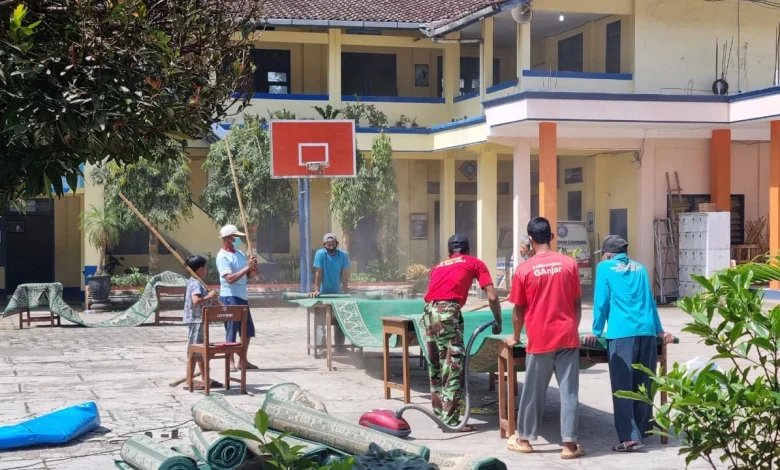 Sejumlah warga dan pemuda bergotong royong membersihkan dan menjemur karpet masjid di halaman terbuka menjelang Iduladha 1447 H.
