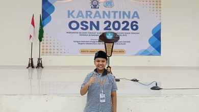 Anagha Damar Ranu siswa SD Muhammadiyah Palur berpose mengepalkan tangan di depan panggung Karantina OSN 2026.