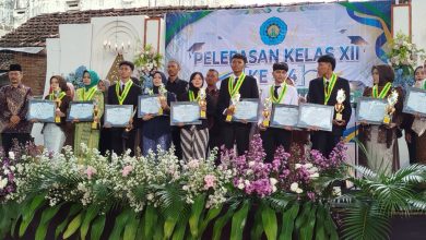 Sepuluh lulusan terbaik SMK Muhammadiyah 01 Keling Jepara berdiri di atas panggung sambil memegang piala dan piagam penghargaan.
