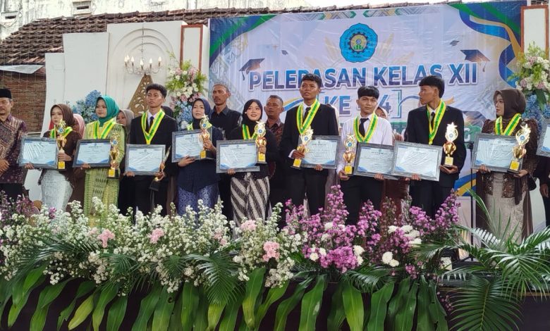 Sepuluh lulusan terbaik SMK Muhammadiyah 01 Keling Jepara berdiri di atas panggung sambil memegang piala dan piagam penghargaan.