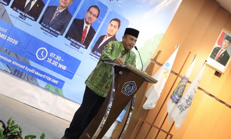 Foto Dr. H. Agung Danarto, M.Ag. berbaju batik hijau dan peci hitam sedang memberikan pemaparan materi Stadium Generale IKA UMS dari atas podium, berlatar spanduk biru acara Rakernas IV di Gedung FEB UMS.