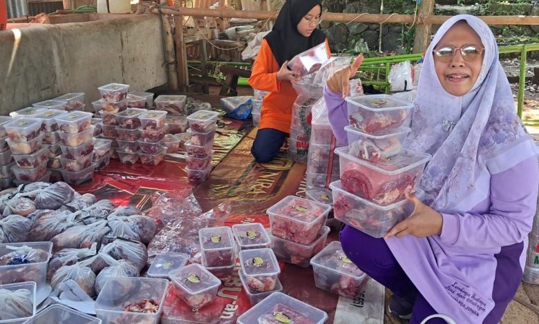 Dua orang panitia perempuan sedang menata tumpukan wadah thinwall transparan berisi daging qurban ramah lingkungan di Masjid Al Raudhoh Kedung Cino Jepara.