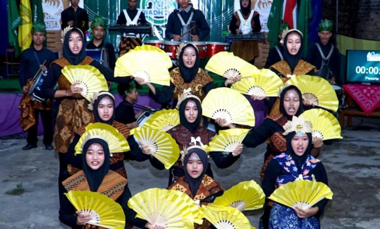 Kelompok peserta remaja masjid mengenakan busana batik bertema alam dan memegang kipas kuning saat tampil dalam kompetisi lomba takbir Idul Adha kreatif AMM Gading.