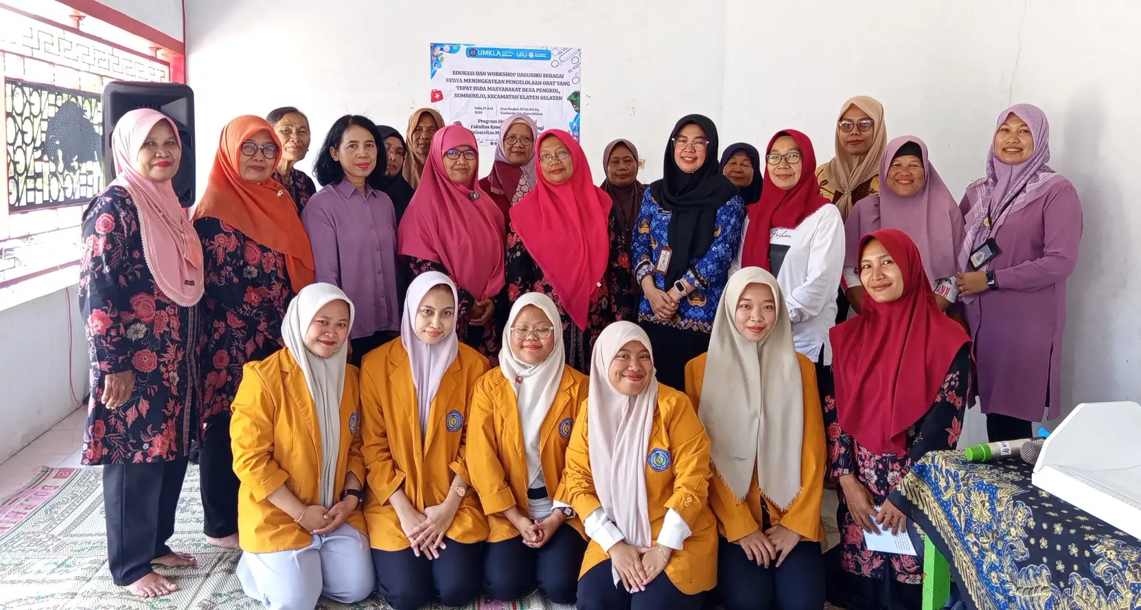 Sekelompok peserta workshop DAGUSIBU di Klaten Selatan yang terdiri dari kader posyandu dan mahasiswa farmasi sedang berpose bersama dengan latar belakang poster edukasi.