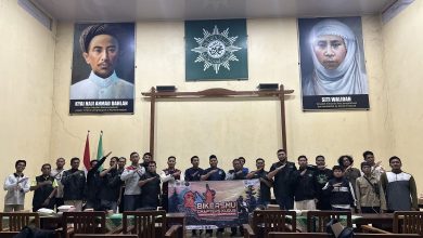 Anggota BikersMu Muria Raya berfoto bersama membentangkan spanduk di dalam ruangan aula berlatar belakang foto K.H. Ahmad Dahlan dan Siti Walidah.