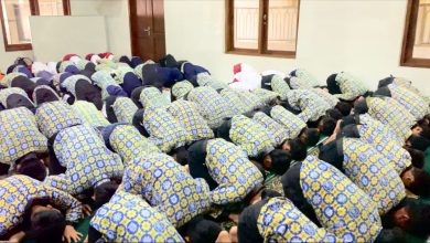 Puluhan siswa SD Muhammadiyah PK Banyudono dalam seragam batik biru-kuning melakukan sujud syukur massal di Masjid Asyiroj. Punggung mereka memenuhi karpet hijau, menciptakan pola mosaik visual yang mengharukan.