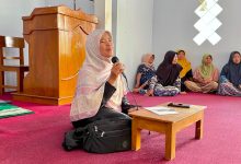 Seorang wanita berjilbab sedang berbicara menggunakan mikrofon saat memberikan penyuluhan kesehatan kepada warga dalam kegiatan Safari Qurban di Desa Mesoyi.