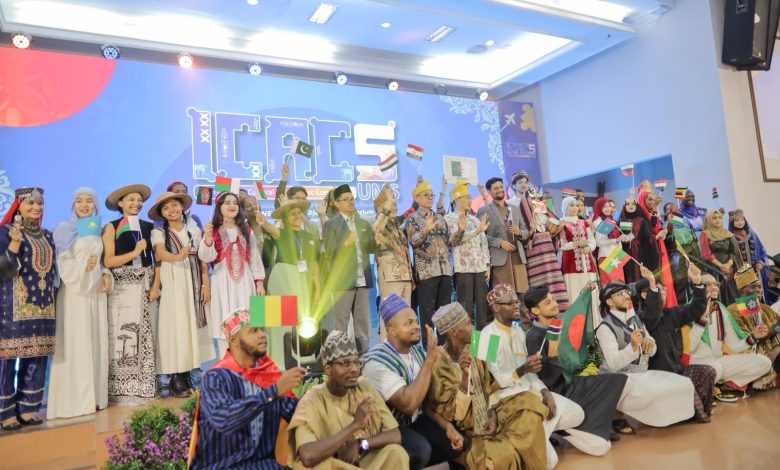 Foto bersama rektor UMS Prof. Dr. Harun Joko Prayitno, M.Hum. dan pimpinan universitas dengan peserta internasional ICAC 2026 yang mengibarkan bendera berbagai negara di panggung audtorium.