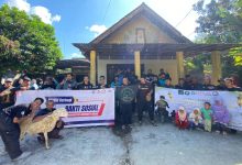 Anggota BikersMu Blitar berfoto bersama dengan spanduk kegiatan Qurban Bareng BikersMu dan bakti sosial pembagian daging qurban siap makan di Kautan Jeding.