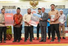 Wamenko Pangan Hanif Faisol Nurofik dan Pengurus Pemuda Muhammadiyah Bogor Memegang Buku di Panggung