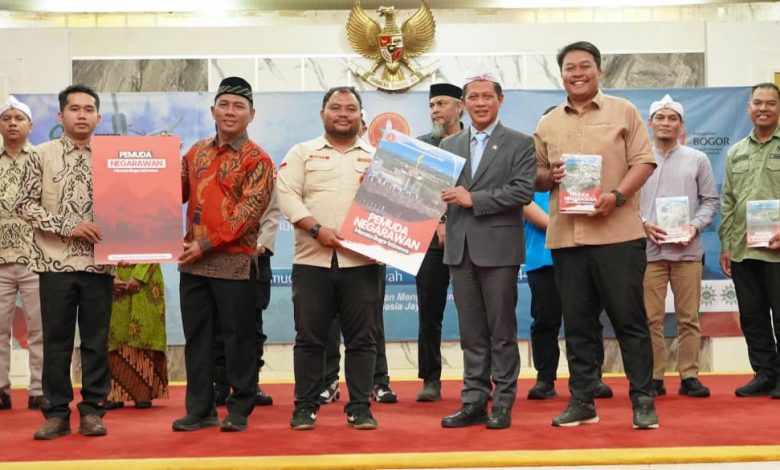 Wamenko Pangan Hanif Faisol Nurofik dan Pengurus Pemuda Muhammadiyah Bogor Memegang Buku di Panggung