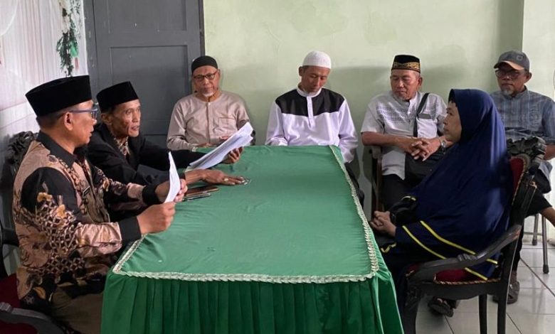 Sebuah pertemuan formal di KUA Nguter menampilkan seorang mualaf wanita berjilbab dan enam pria di sekeliling meja hijau, dengan plakat dinding bertuliskan 'KUA NGUTER - IKrar syahadat' dan sebuah Quran di atas meja.