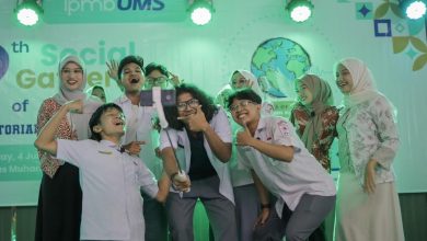 Sekelompok mahasiswa Universitas Muhammadiyah Surakarta (UMS) berswafoto bersama dengan tongkat selfie gimbal di atas panggung dengan spanduk "The 9th Social Gathering of ENGLISH TUTORIAL PROGRAM" dan logo perdamaian, di bawah pencahayaan panggung hijau. Foto ini menangkap kegembiraan dan ekspresi perdamaian global melalui kreativitas mahasiswa.