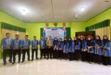 Foto bersama guru SMA Muhammadiyah 1 Simo mengenakan seragam batik biru dalam acara IHT Integrasi Coding dan Artificial Intelligence di aula sekolah. Di tengah barisan tampak narasumber berbaju krem dan Kepala Sekolah Ibu Dwitya Nadia Fatmawati berdiri di depan spanduk acara resmi.